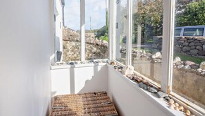 A corner room with a large window, a wicker bench, and a stone wall outside. - 2 Bed in Caernarfon (oc-92082) (Aberdesach)