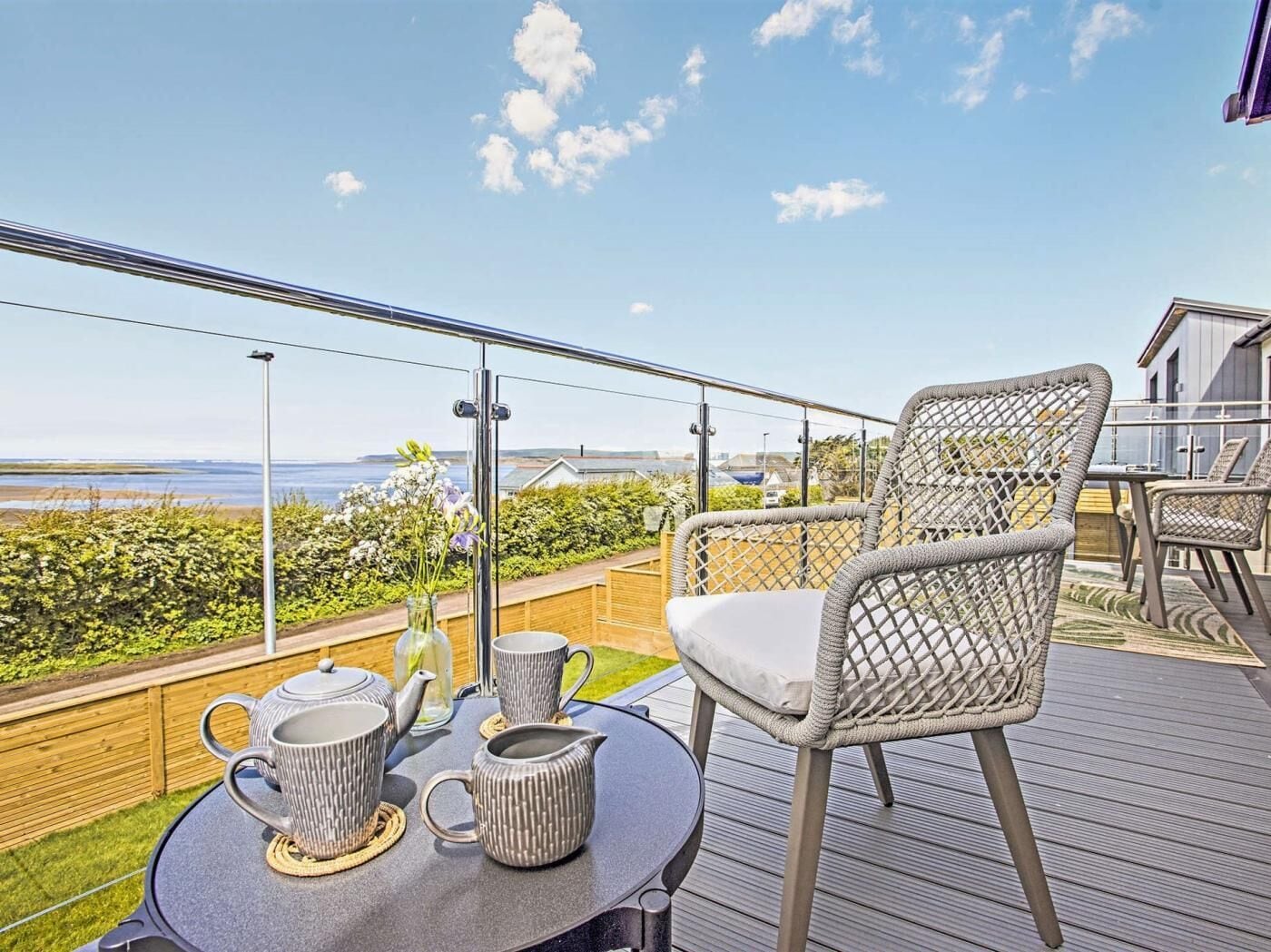 Ein Balkon mit Korbstühlen, einem Tisch mit Teeservice und Blick aufs Meer.