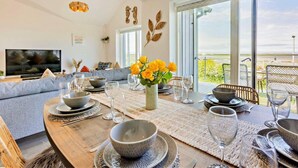 Una sala de estar moderna con comedor, ventanas grandes y vistas al exterior.