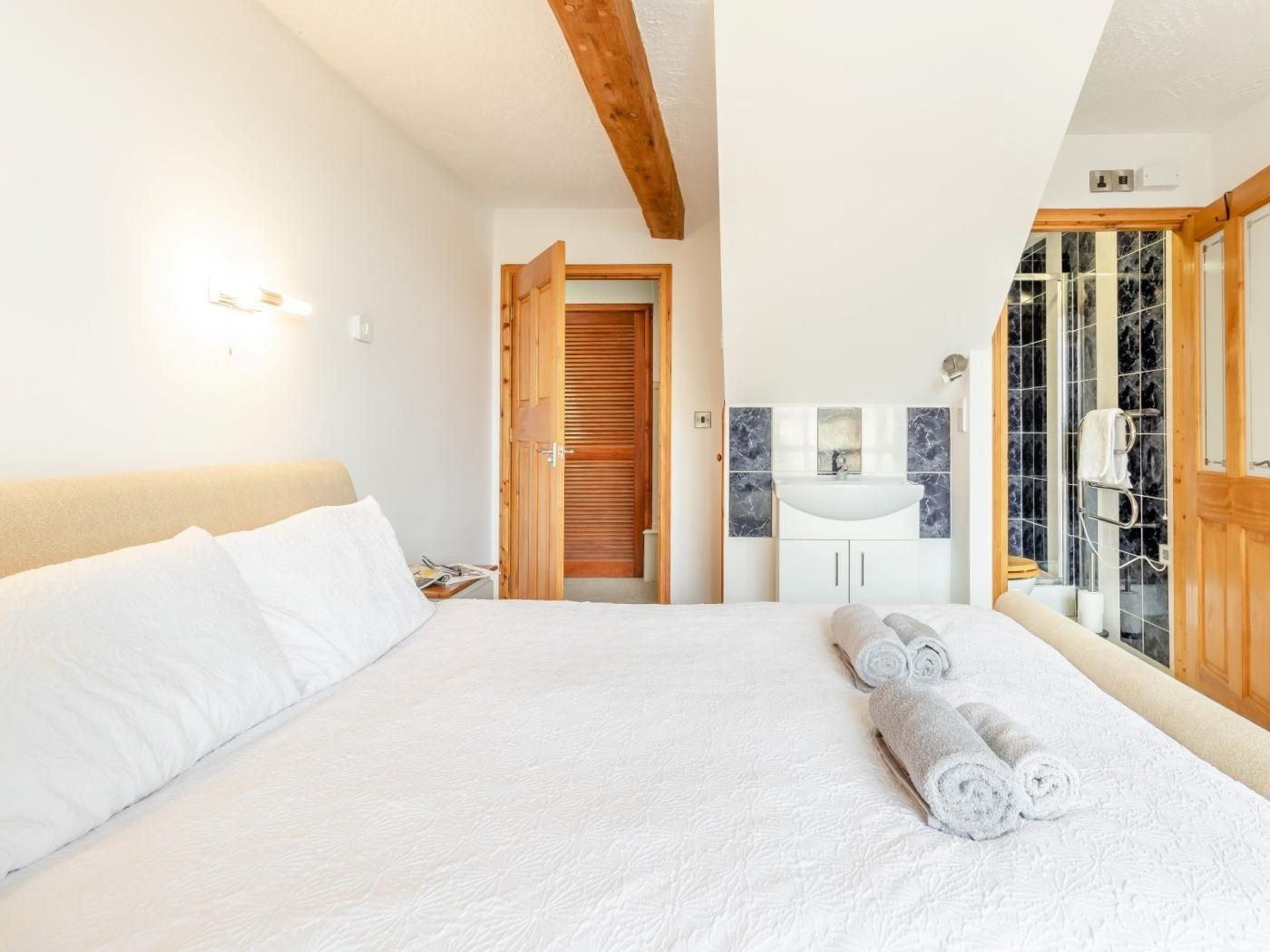 Ein Hotelzimmer mit Bett, Badezimmer mit Waschbecken und Spiegel sowie einer Duschkabine.