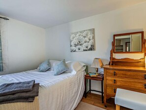 A bedroom with a bed, a nightstand, a dresser, a mirror, and a wall art piece.