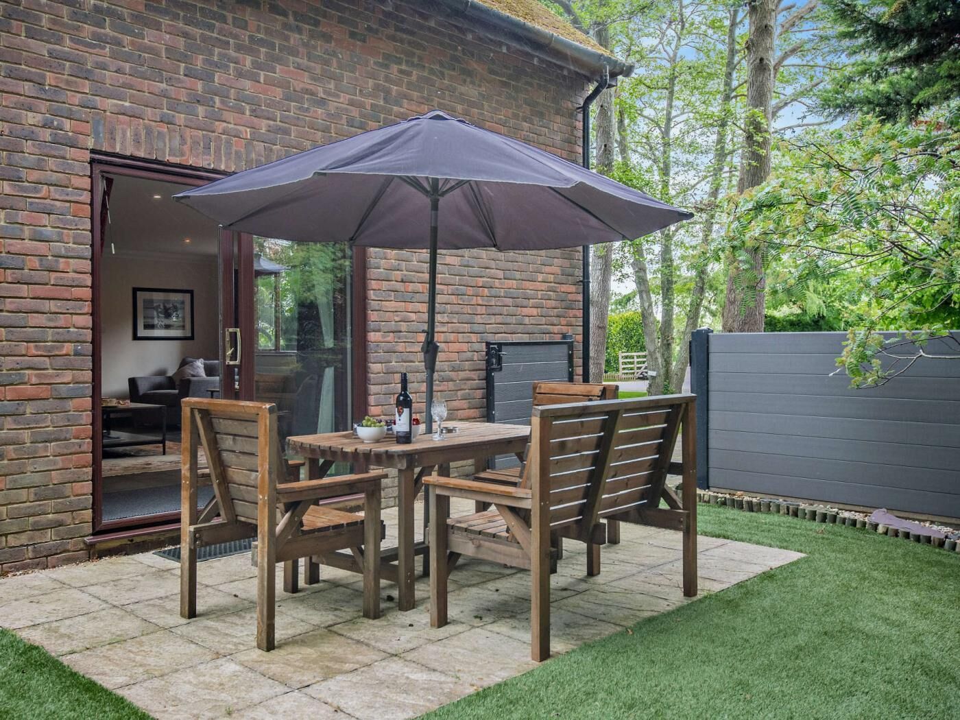A patio with a table and chairs, a large umbrella, and a brick wall.