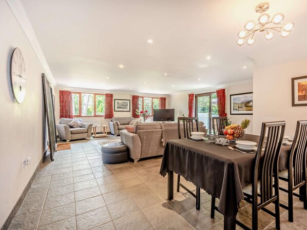 A spacious living area with a dining table, sofas, and a television. - 2 Bed in Christchurch (oc-91999) (Burton)