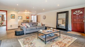 Ein geräumiges Wohnzimmer mit grauem Sofa, einem Couchtisch und einem großen Spiegel.