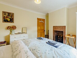 Ein Schlafzimmer mit Bett, Kommode, Spiegel und Kamin.