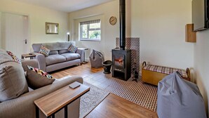 Ett mysigt vardagsrum med en soffa, ett bord, en öppen spis och ett fönster.