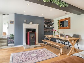 A modern living room with a fireplace, a dining table, and a bench. - 3 Bed in Brecon (oc-92320) (Llandeilo'r-Fan)
