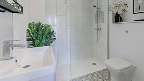 Ein modernes Badezimmer mit Duschkabine aus Glas, einem weißen Waschbecken und einer Toilette.