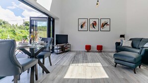 Ein modernes Wohnzimmer mit Essbereich aus Glas, einem Flachbildfernseher und abstrakter Wandkunst.