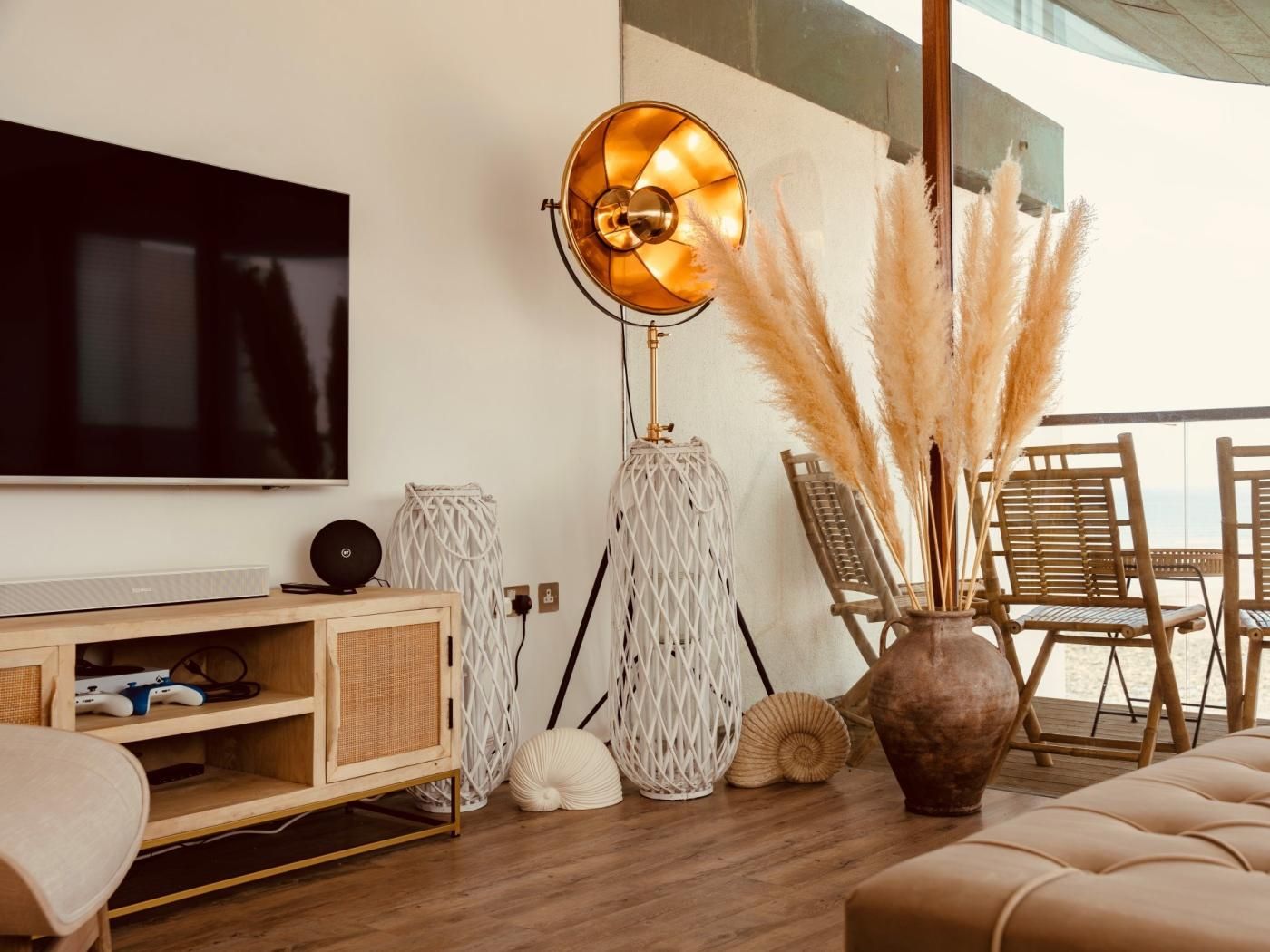 Een moderne woonkamer met een flatscreen televisie, een vloerlamp en een zithoek met stoelen en een bank.
