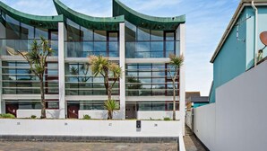 Een modern gebouw met een golvend dak, grote ramen en een geplaveid binnenterrein.