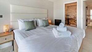 Een hotelkamer met een groot bed, een nachtkastje met een lamp en uitzicht op de badkamer.