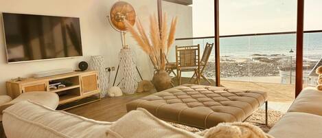 Un salon moderne doté d’un grand téléviseur à écran plat, d’un canapé confortable, d’une table basse et offrant une vue sur la plage.