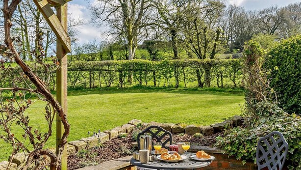 Een terras met een ontbijttafel, een stoel en een pergola.