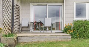 Een terras met een tafel, stoelen, een whiteboard en een schuifdeur die naar een kamer leidt.