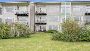 Un edificio residencial de varios pisos con un patio central, balcones y una pequeña área ajardinada.
