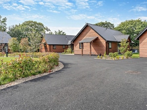 A row of wooden cabins with pitched roofs, a gravel driveway, and a landscaped garden area. - 2 Bed in Swansea (oc-91728) (Upper Killay)