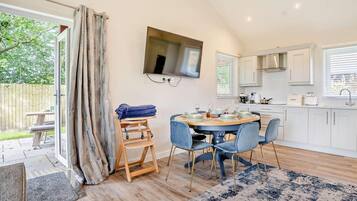 A modern kitchen with a dining area, wooden flooring, and a large window.