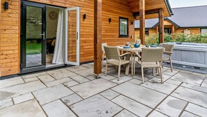 Eine Holzdiele mit Terrasse, einer Schiebetür und einem Whirlpool.
