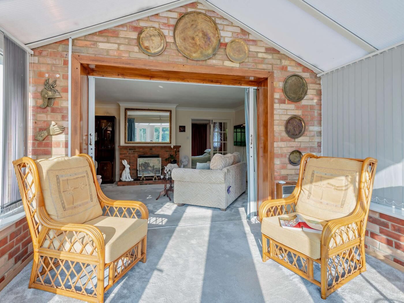 A covered porch with wicker chairs, a fireplace, and decorative plates on the wall.