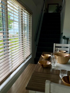 Un comedor con una mesa lista para dos personas, con cuencos y vasos de madera.
