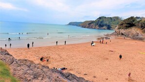 Une plage animée, un rivage rocheux et un ciel dégagé.