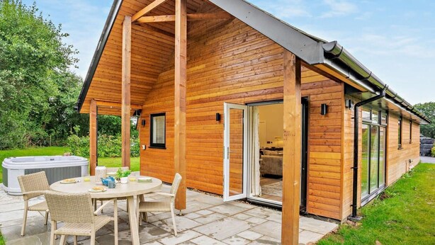 Une cabane en bois dotée d’un patio couvert, d’un bain à remous et d’un coin repas.