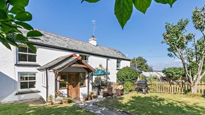 A white building with a wooden front porch, a small garden, and a pathway leading to the entrance. - 3 Bed in Truro (oc-91792) (Truro)