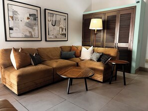 Un salón con un sofá modular, una mesa de centro redonda y dos cuadros abstractos enmarcados en la pared.