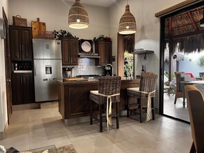 Una cocina moderna con alacenas de madera oscura, electrodomésticos de acero inoxidable y una isla central con dos sillas de mimbre.