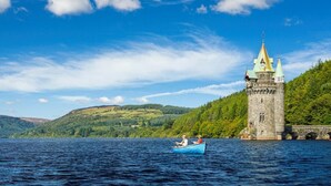 Un castillo junto a un lago con un bote al frente.