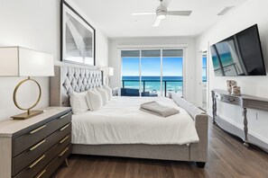 Ein Schlafzimmer mit einem großen Bett, einem Deckenventilator, einem Fernseher und Blick aufs Meer.