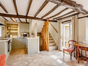 A kitchen with a wooden ceiling, a dining area with a table and chairs, and a staircase leading to an upper level. - 1 Bed in Stamford (oc-92406) (Ketton)