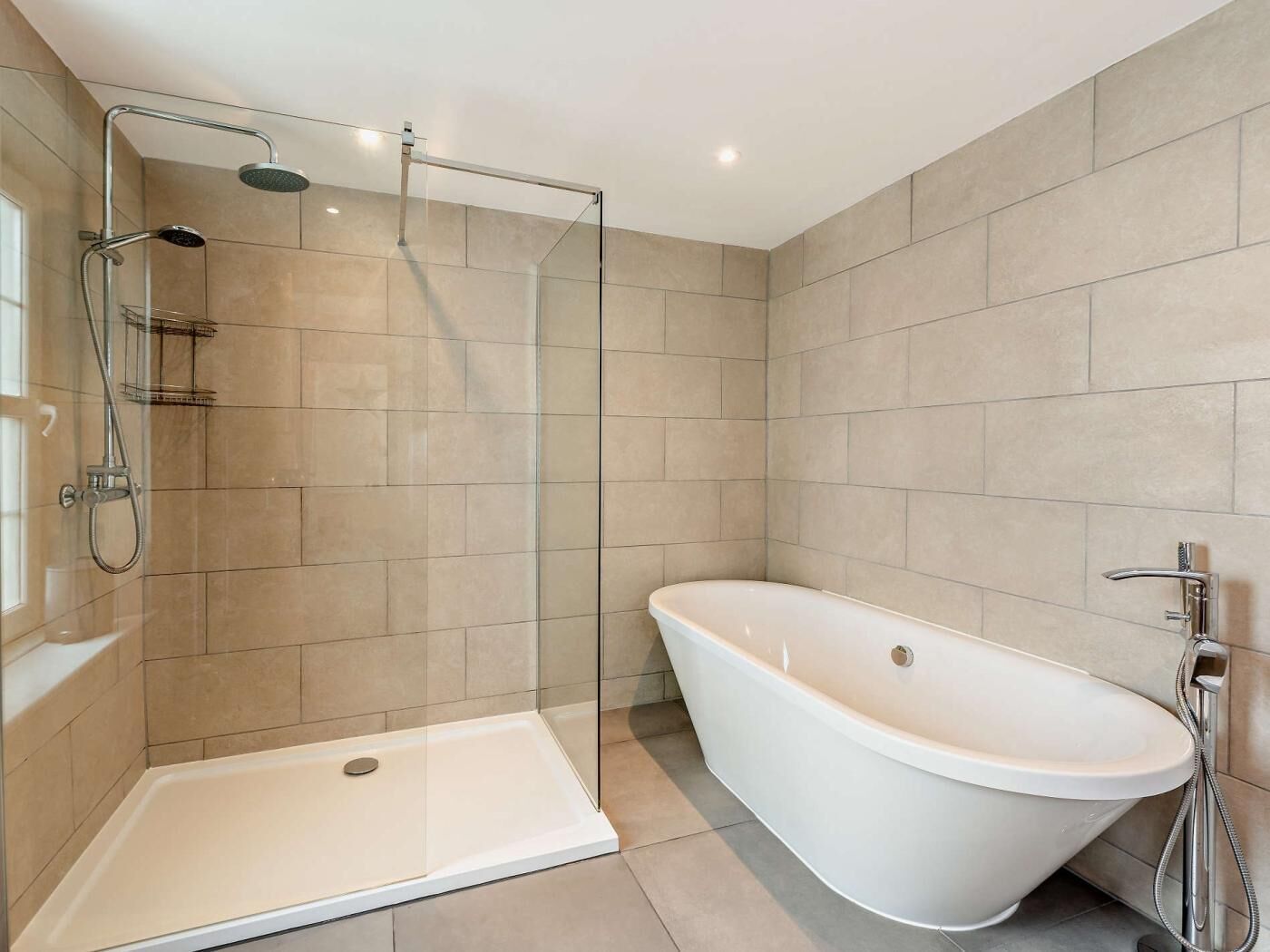 Une salle de bain moderne avec une douche à l’italienne, une baignoire sur pieds et des murs carrelés.