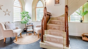 Ein geräumiges Wohnzimmer mit einer Holztreppe, großen Fenstern und einer gemütlichen Sitzecke.