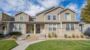 A two-story house with a stone facade, a front porch, and a well-maintained lawn. - Spacious 3BR Home w/Garage - Easy DIA Access (Commerce City)