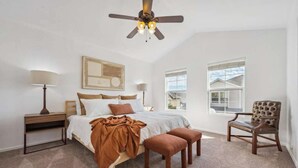A bedroom with a bed, a chair, a nightstand, a lamp, a ceiling fan, and a window. - Spacious 3BR Home w/Garage - Easy DIA Access (Commerce City)