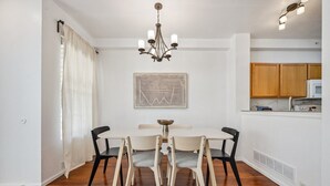 A dining area with a table and chairs, a chandelier, a kitchen with wooden cabinets, and a microwave. - Spacious 3BR Home w/Garage - Easy DIA Access (Commerce City)