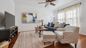 A living room with a flat-screen TV, a ceiling fan, a sofa, a coffee table, and a rug. - Spacious 3BR Home w/Garage - Easy DIA Access (Commerce City)