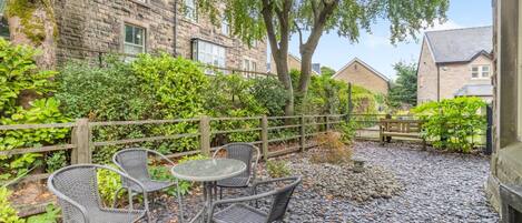 A courtyard with stone flooring, wicker chairs, and a table.