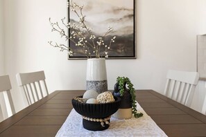 A dining table with a vase of branches, a bowl of decorative items, and a framed picture on the wall. - Heated Pool, PickleBall - New & Beautiful - Save Today (Washington)