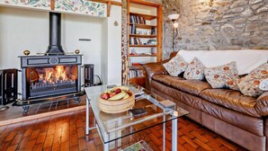Ein gemütliches Wohnzimmer mit Kamin, einer Ledersofa, einem Glastisch und einer Steinwand.