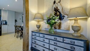 Une pièce avec un meuble en bois, un tableau représentant un cheval et deux lampes.