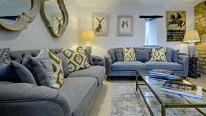 Un salon avec deux canapés, une table basse, des œuvres d’art murales et une lampe.