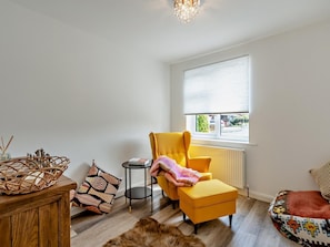A room with a yellow armchair, a small round table, a wicker basket, and a patterned rug. - 2 Bed in Poulton-le-fylde (oc-92095) (Knott End-on-Sea)