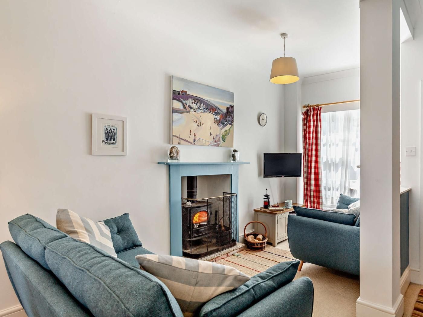 A living room with a fireplace, a sofa, a television, and a window with curtains.