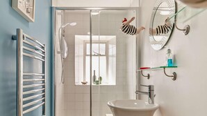 Ein Badezimmer mit Duschkabine aus Glas, einem weißen Waschbecken, einem Spiegel und einem Handtuchhalter.