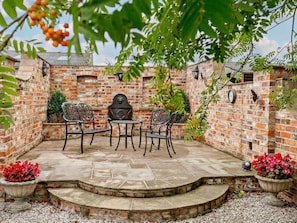 Eine Terrasse mit Ziegelmauern, einem runden Tisch und vier Stühlen.