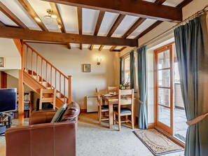 A cozy living room with a wooden staircase, a dining area, and a view through a glass door. - 1 Bed in York (oc-92093) (High Catton)