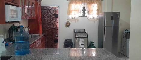 A kitchen with granite countertops, a stainless steel refrigerator, a gas stove, and a microwave.